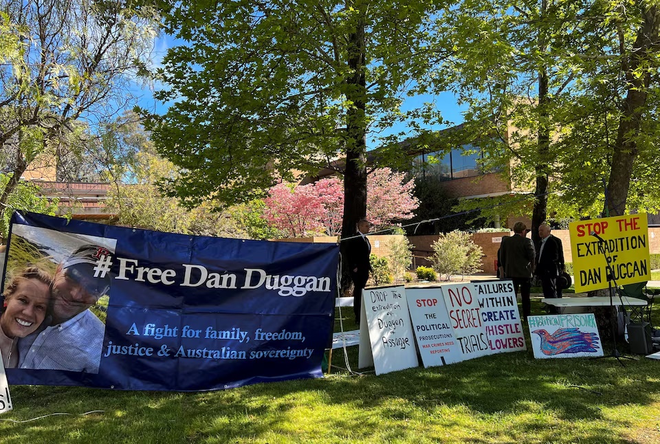  People interact near signs placed during a demonstration in support of former U.S. Marine Corps pilot Daniel Duggan outside the Federal Court of Australia, on the day Duggan appeals against extradition to the U.S. on charges of violating U.S. arms control laws related to China, in Canberra, Australia, October 16, 2025. REUTERS/Peter Hobson 