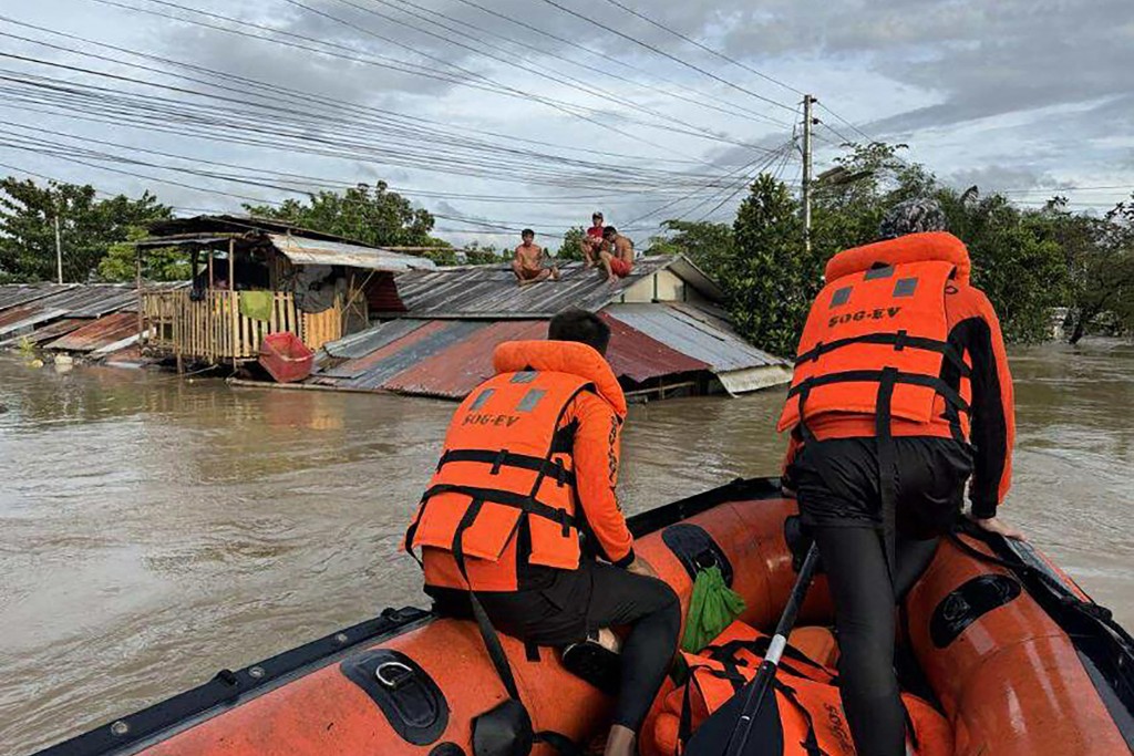This handout photo taken on September 26, 2025 and released on September 27 by the Philippine Coast Guard shows coast guard personnel rescuing residents from their flooded house at the height of Severe Tropical Storm Bualoi, at a village in Ormoc City, Leyte province.  (Photo by Handout / Philippine Coast Guard (PCG) / AFP) 