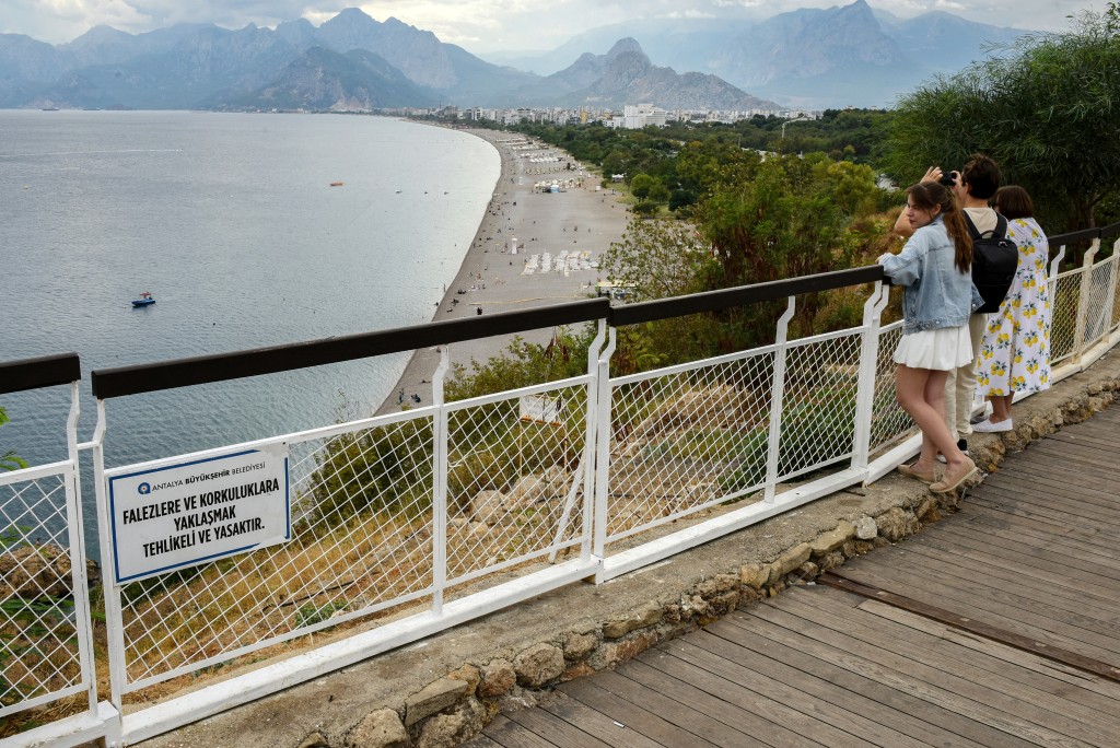 Photo by GOKSEL YAPAR / AFP  People look at the view and pictures of the Konyaalti beach in Antalya, on October 1, 2026.