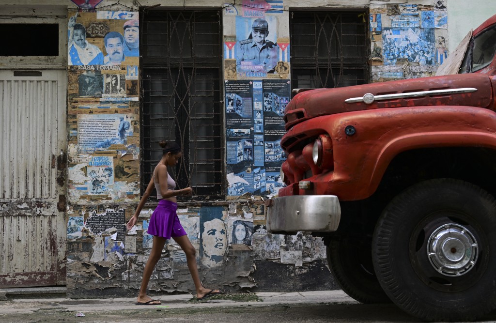 A woman walks past posters depicting Venezuelan President Nicolas Maduro, Venezuela's late former president Hugo Chavez, former Cuban president Raul Castro and Cuba's late former leader Fidel Castro in Havana on October 19, 2026. (Photo by YAMIL LAGE / AFP)