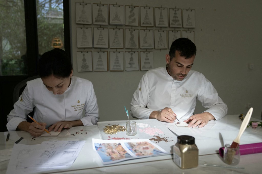Photo by THOMAS SAMSON / AFP  French pastry chef Bastien Blanc-Tailleur creates decorations for a wedding cake at his studio in Saint-Remy-les-Chevreuse, southwestern Paris on April 10, 2026.