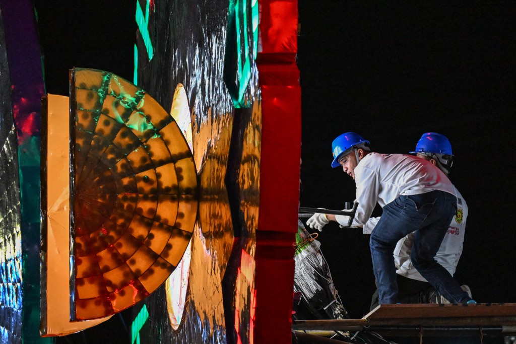 Photo by JAM STA ROSA / AFP  This photo taken on December 14, 2025, shows men working on the lights behind the giant lantern during the Giant Lantern Festival in San Fernando, Pampanga.