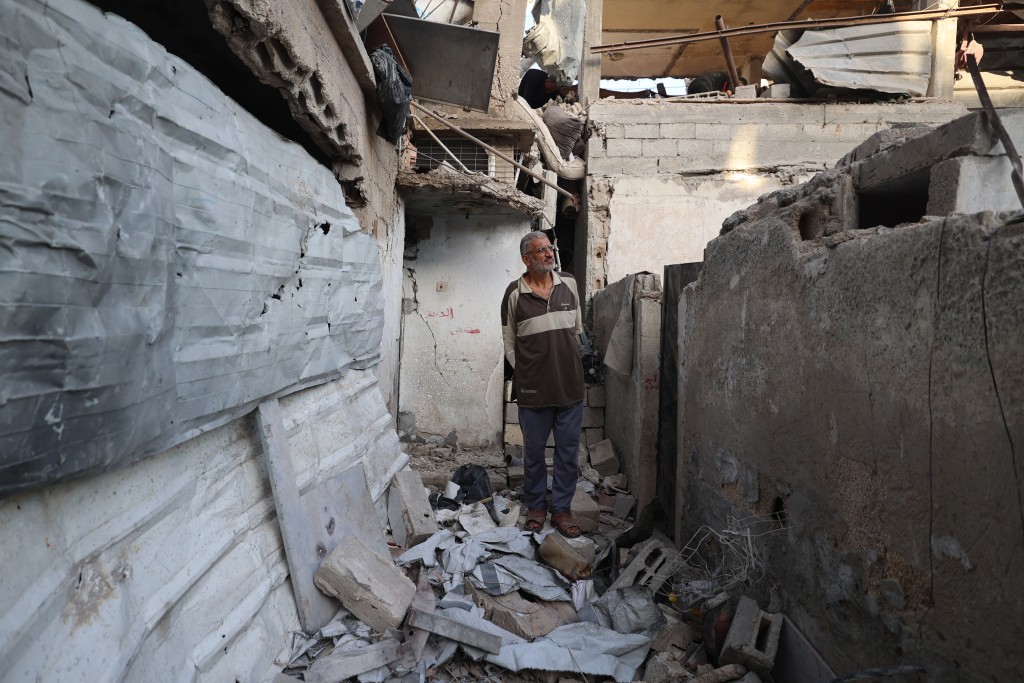 Photo by EYAD BABA / AFP.  A Palestinian man inspects the damage around his home after an Israeli strike targeted the previous day the Bureij refugee camp in the central Gaza Strip, on October 20, 2025.