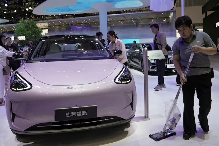 A staff member cleans the floor next to a Geely GEOME Xingyuan electric vehicle (EV), also known as Geely EX2, displayed at the Beijing International Automotive Exhibition, or Auto China, in Beijing, China April 26, 2026. REUTERS/Xiaoyu Yin