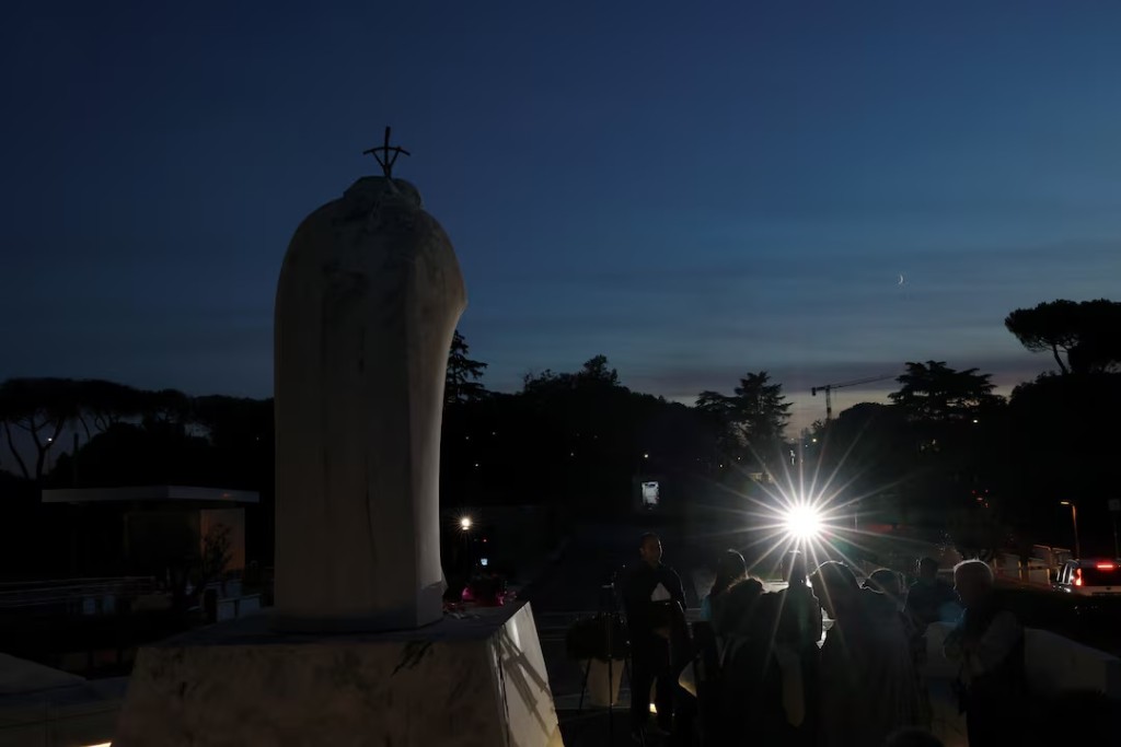  People gather near the statue of the late Pope John Paul II outside Gemelli Hospital, where Pope Leo is being treated for lung cancer following surgery to remove part of his right lung, in Rome, Italy, October 14, 2026. REUTERS/Yara Nardi