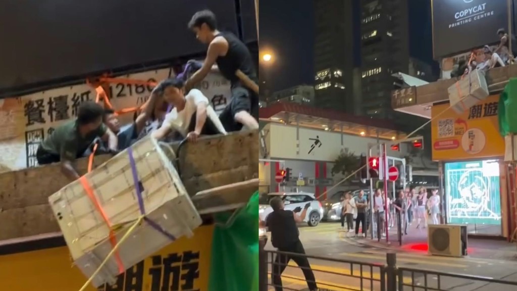 Workers haul a split-type air conditioner up a building canopy using ropes.