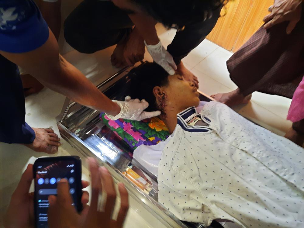 In this March 30, 2021 photo provided by Dawei Watch news outlet, a relative points to an open wound in the neck of 17-year old Kyaw Min Latt in Dawei, Myanmar. His March 27, 2021 shooting by a soldier was captured on CCTV cameras and shared through social media. 