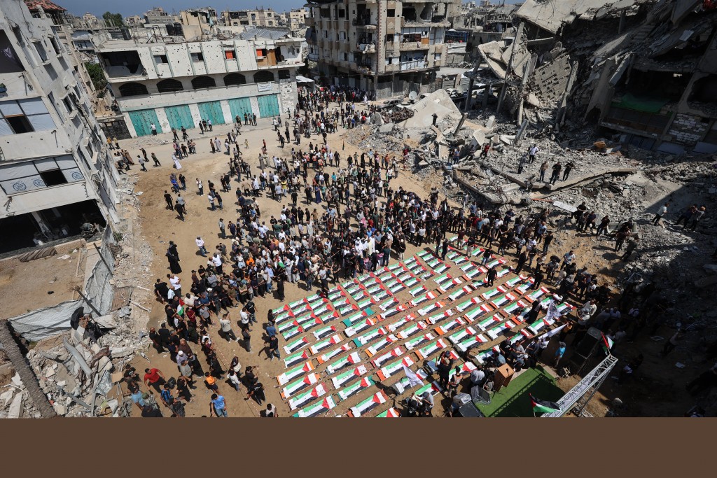 Photo by OMAR AL-QATTAA / AFP Palestinian mourners attend the funeral of members of the Abu Sharia and al-Hasayna families, whose remains were recently recovered from the rubble of residential buildings in the al-Sabra neighbourhood which were struck by Israeli bombardments in November 2023, in Gaza City on August 4, 2026.