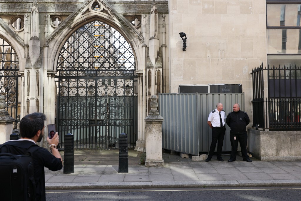 Security guards stand in front a screen covering a new mural by anonymous artist Banksy on the Royal Courts of Justice in London, Britain. (Reuters)