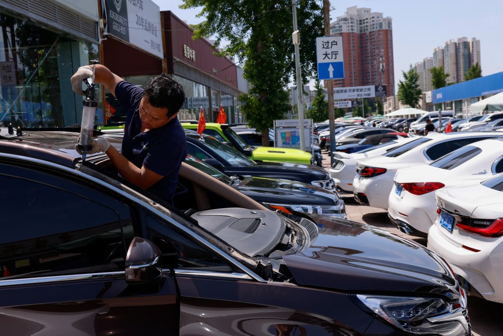 An employee repairs a second hand car at a used car market in Beijing, China June 6, 2025. REUTERS/Tingshu Wang