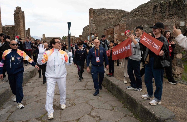 Jackie Chan waves to fans as he carries the Olympic Torch at the archaeological area of Pompeii. AFP
