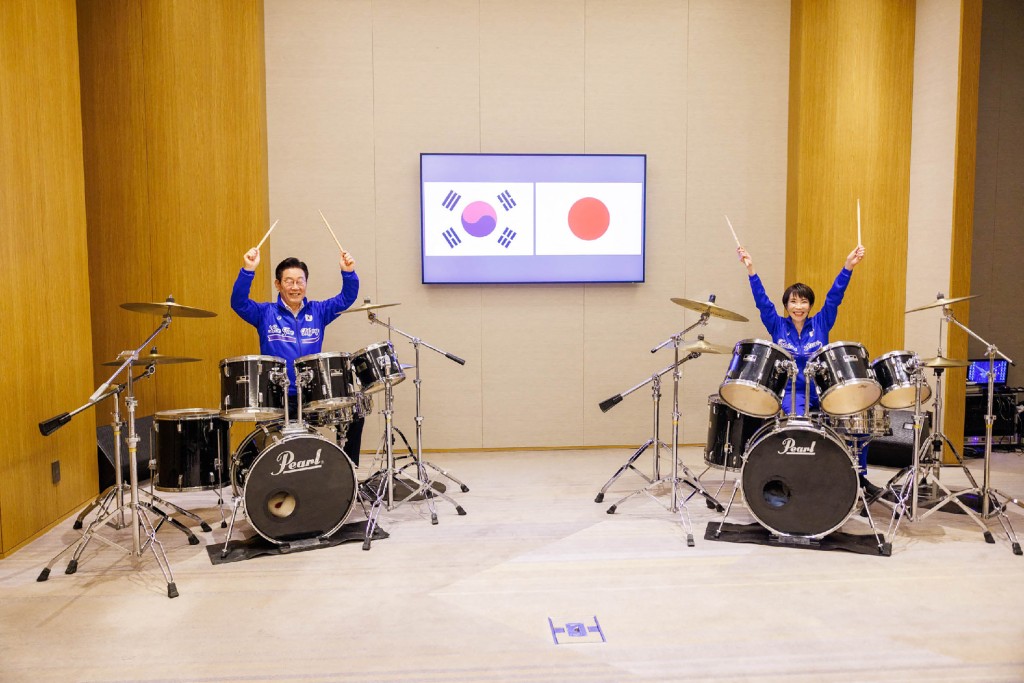 Photo by HANDOUT / VARIOUS SOURCES / AFP  This handout photo taken on January 13, 2026 and released from Japan's Government Public Relations Office via Jiji Press shows South Korea's President Lee Jae Myung (L) and Japan's Prime Minister Sanae Takaichi playing drums, in Nara, Nara Prefecture.