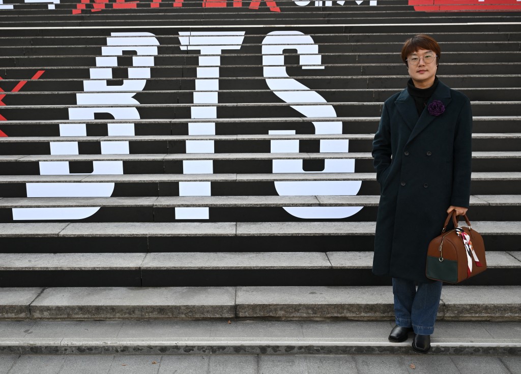 Photo by JUNG YEON-JE / AFP  This picture taken on March 10, 2026 shows traditional Korean artist Sung Young-rok, a fan of K-pop boy group BTS, posing in front of the stairs displayed with the BTS logo during an interview with AFP at Gwanghwamun Square in Seoul.