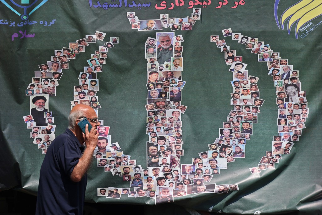 Photo by ATTA KENARE / AFP  A man walks past a banner installed along the roadside in Tehran on April 29, 2026.