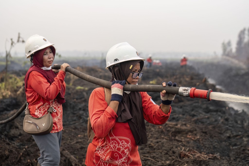 Photo by HERIBERTUS / AFP Members of the all-women The Power of Mama (TPoM) volunteer firefighting team spray water onto smouldering peatland in Mensubuk Lama, Tanjungpura Village, Ketapang Regency, West Kalimantan on September 26, 2026.