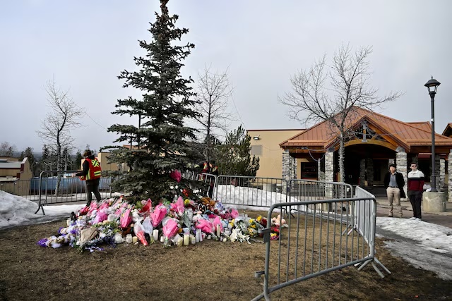 Workers install a fence around a makeshift memorial for the victims two days after a deadly mass shooting took place at a school in the town of Tumbler Ridge, British Columbia, Canada, February 12, 2026. REUTERS/Jennifer Gauthier