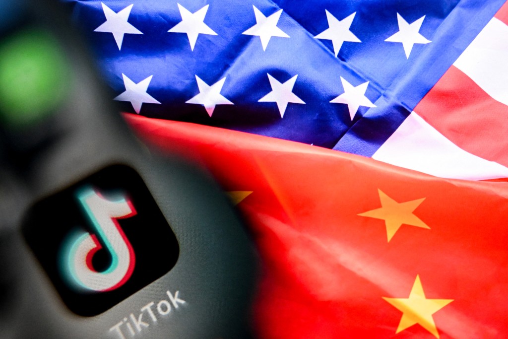 A photo taken on April 10, 2025 shows the Chinese social networking service TikTok's logo on a smartphone screen (L) and US and China flags combo illustration on a laptop screen in Frankfurt am Main, western Germany. (Photo by Kirill KUDRYAVTSEV / AFP)