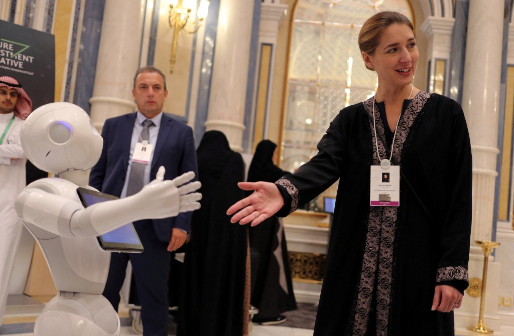 Aurore Chiquot of SoftBank Robotics Europe extends her hand to a robot during the Future Investment Initiative conference in Riyadh, Saudi Arabia October 25, 2017. (Reuters)