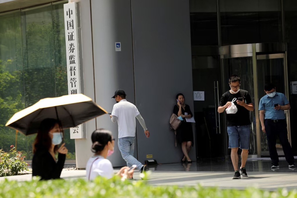 People walk past the China Securities Regulatory Commission (CSRC) sign at its building on the Financial Street in Beijing, China July 9, 2021. REUTERS