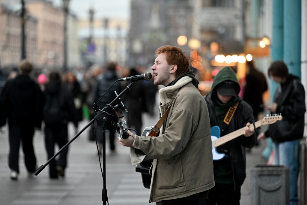 Arseny, a 21-year-old street musician, performs in central Saint Petersburg on October 27, 2025. (Photo by Olga MALTSEVA / AFP)