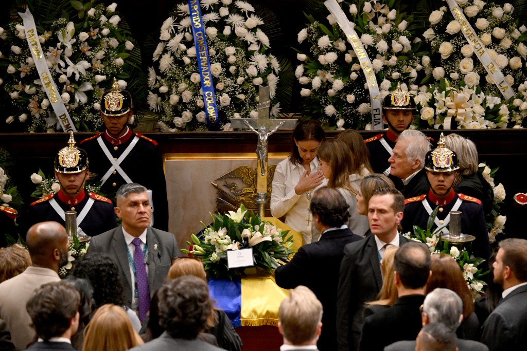 Maria Claudia Tarazona (C), the widow of late Colombian presidential candidate Miguel Uribe, and relatives mourn next to his body lying in state at Congress in Bogota on August 11, 2025. (Photo by Raul ARBOLEDA / AFP)