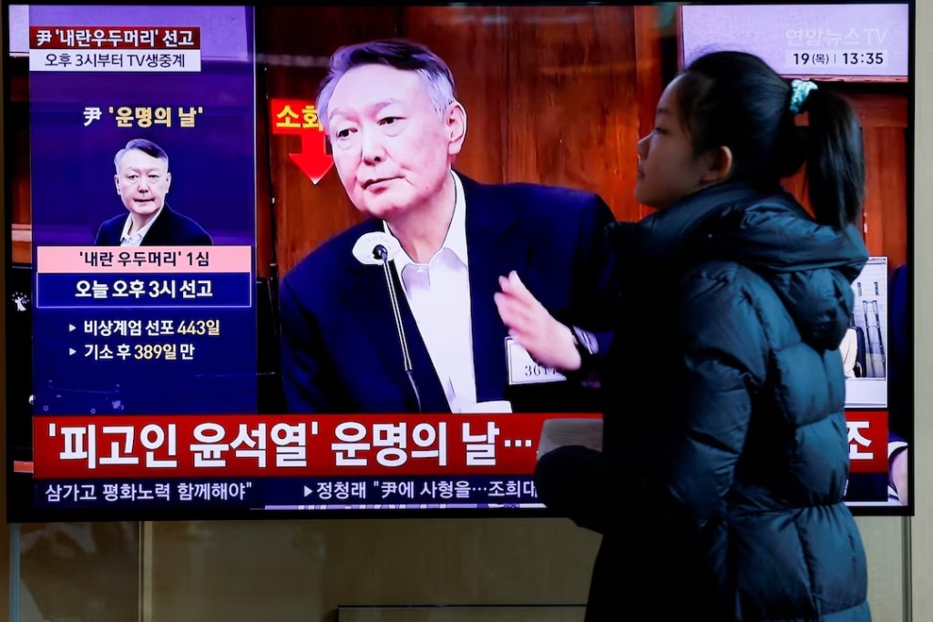 A person walks in front of a TV screen broadcasting a news report on the sentencing trial of South Korean former president Yoon Suk Yeol's insurrection case, stemming from his short-lived declaration of martial law in December 2024, in Seoul, South Korea, February 19, 2026. REUTERS/Kim Soo-hyeon 