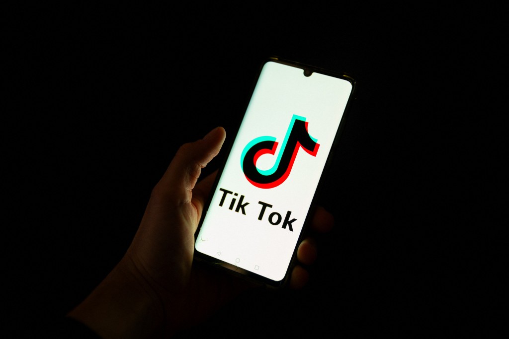 Photo by ANTONIN UTZ / AFP  This photograph taken on April 19, 2024 shows a man holding a smartphone displaying the logo of Chinese social media platform TikTok in an office in Paris