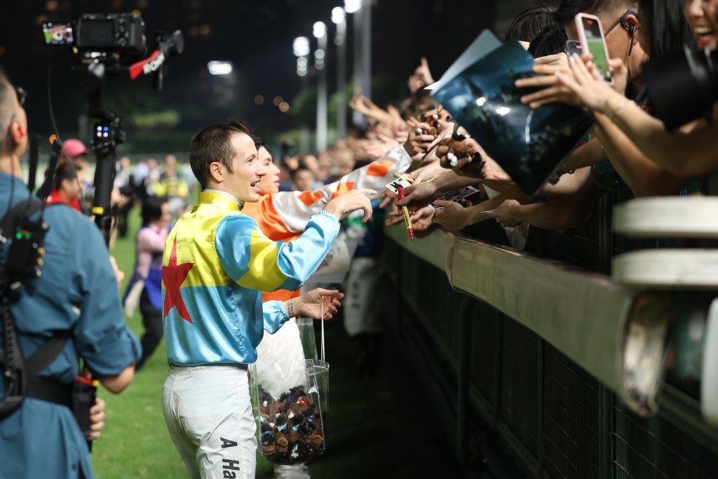 Jockeys hand out souvenirs with a full house of racegoers. (Sing Tao)