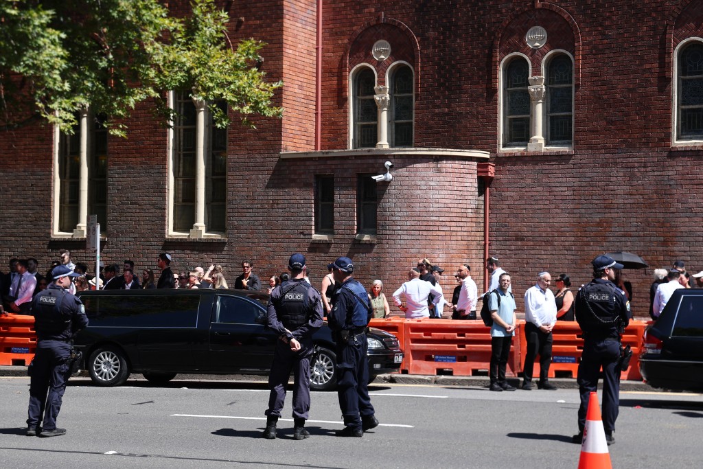 Photo by DAVID GRAY / AFP  Police stand guard after the funeral of Boris and Sofia Gurman, who were killed in the December 14 Bondi Beach shooting attack, in Sydney on December 19, 2025.
