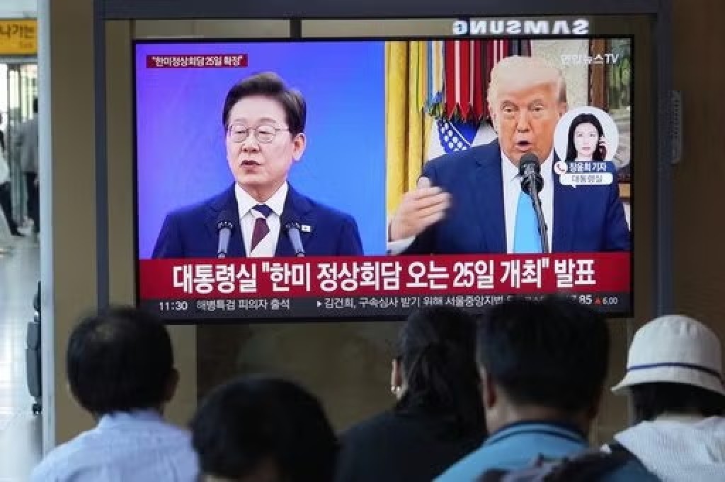 People watch a TV screen showing a file image of South Korean President Lee Jae Myung, left, and U.S. President Donald Trump during a news program at the Seoul Railway Station in Seoul, South Korea, Tuesday, Aug. 12, 2025. The signs read, "The presidential office announced that the South Korea-U.S. summit will be held on the 25th." (AP Photo/Ahn Young-joon)