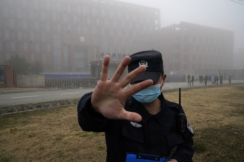 A security guard moves journalists away from the Wuhan Institute of Virology after a World Health Organization team arrived for a field visit in Wuhan in China's Hubei province on Wednesday, February 3, 2021. The WHO team is investigating the origins of the coronavirus pandemic has visited two disease control centers in the province.