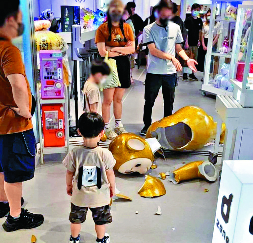 The five-year-old boy looks on despondently as his parents discuss the shattered Teletubby with a staff member of KKplus toy shop in Langham Place. Below, the shop manager and, right, the receipt for the broken statue. Sing Tao