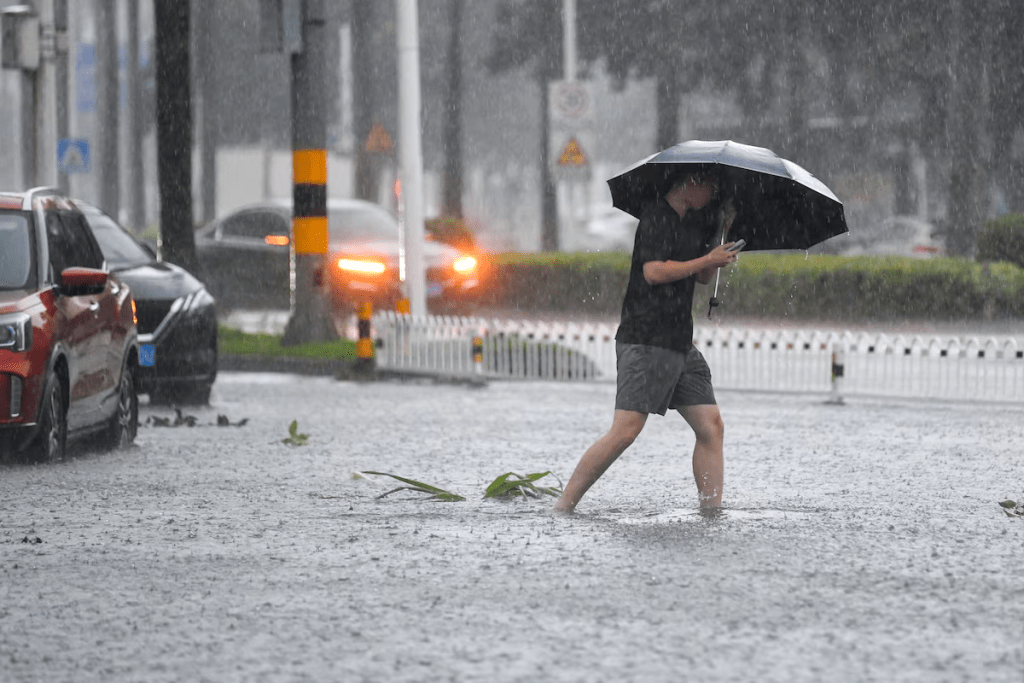 A man braves the rain as he makes his way through a flooded section of the road amid heavy rainfall brought by Typhoon Matmo, in Haikou, Hainan province, China October 5, 2025. cnsphoto via REUTERS