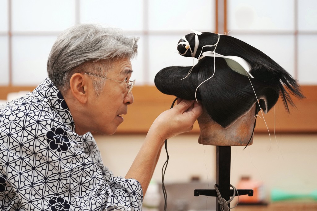 Photo by KAZUHIRO NOGI / AFP  This photo taken on March 11, 2026 shows wig master Tadashi Kamoji creating a wig for kabuki actors at his atelier in Tokyo.