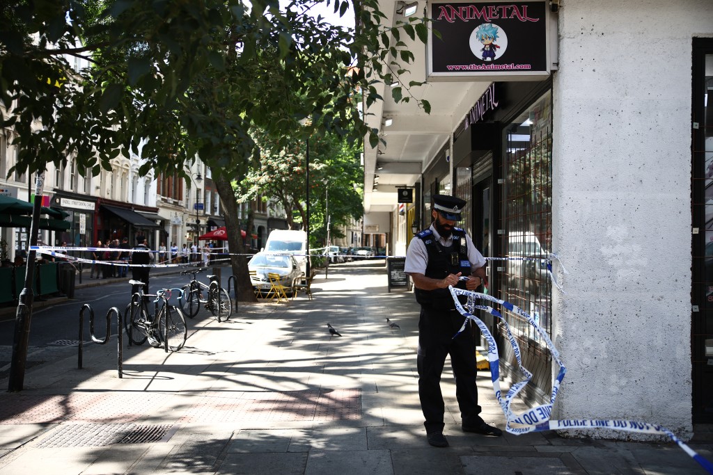 A Police Community Support Officers (PCSO) removes police tape from a cordon, at Endell road in covent garden, central London on August 5, 2026. (AFP)