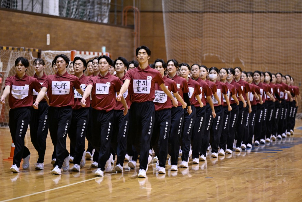 Photo by GREG BAKER / AFP  Students of Nippon Sports Science University rehearse for their annual synchronised walking performance, known as Shudankodo, in Yokohama on November 26, 2025.