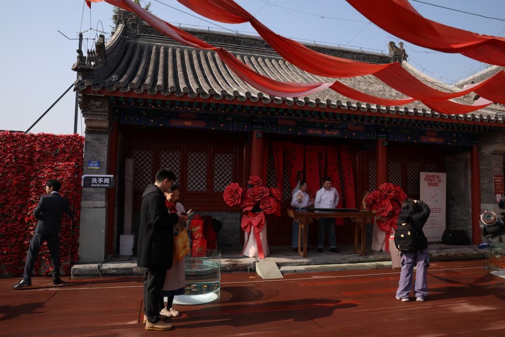 Newlywed couples pose for pictures at the Huguo Guanyin Temple, an outdoor marriage registration site in Beijing, China, October 28, 2025. REUTERS/Tingshu Wang