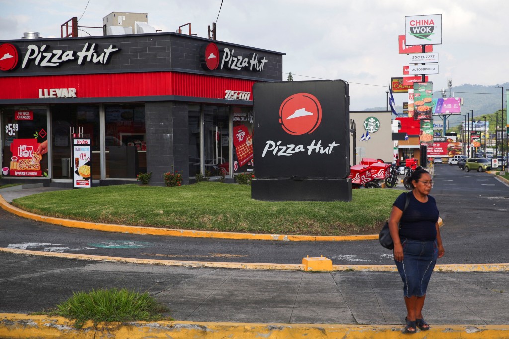 A woman waits to cross a street in front of a Pizza Hut restaurant in San Salvador, El Salvador, September 26, 2024. REUTERS