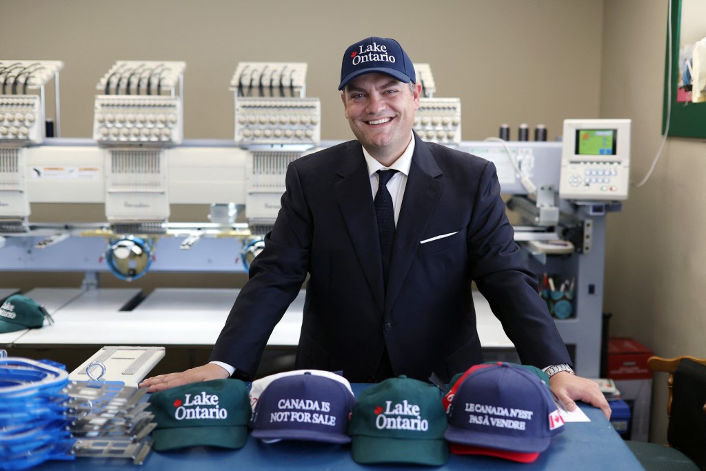 Photo by DAVE CHAN / AFP  Liam Mooney, CEO and strategic leader of Jackpine Dynamic Branding and creator of the "Lake Ontario" cap, poses for a portrait in Ottawa, Ontario, on September 1, 2026.