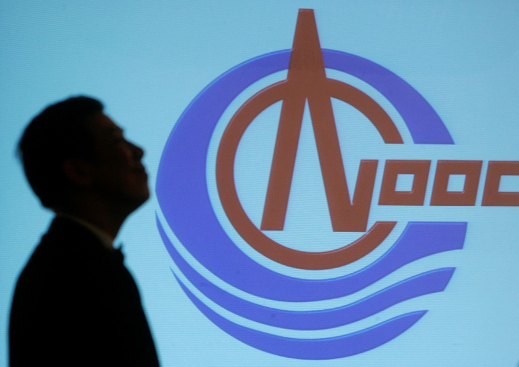 A man walks past a screen with the projected logo of CNOOC Ltd. during a news conference for the 2006 annual results announcement in Hong Kong March 29, 2007.    REUTERS/Paul Yeung  (CHINA)/File Photo