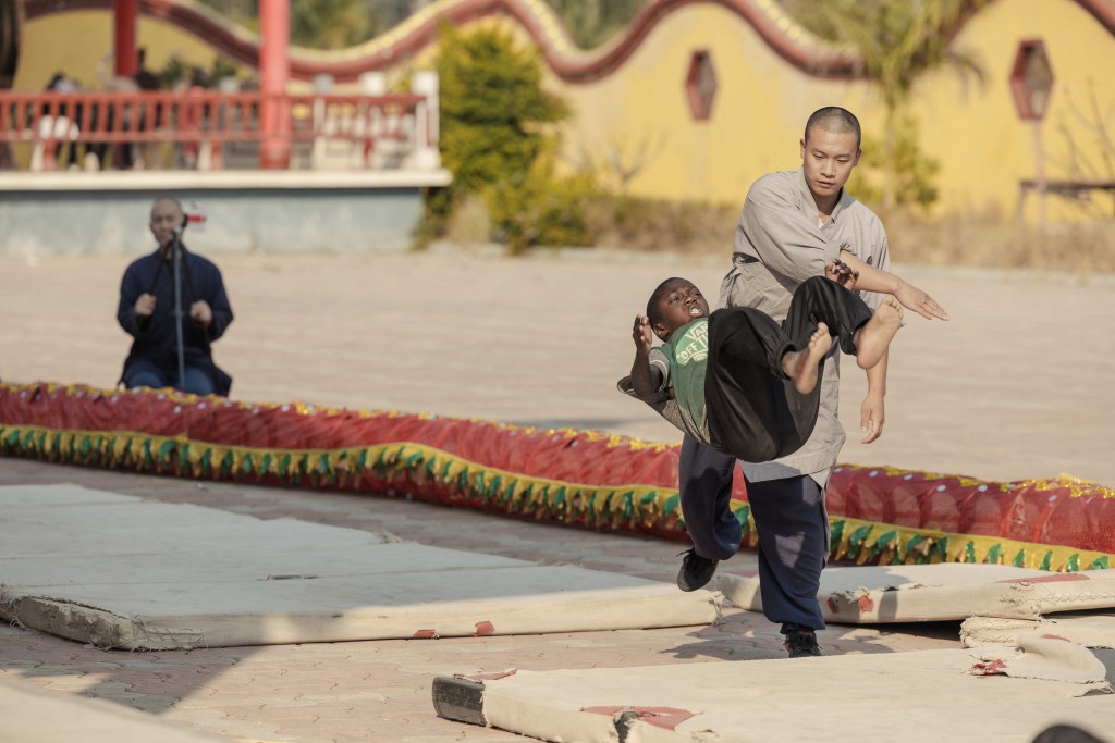 Photo by GIANLUIGI GUERCIA / AFP  Shaolin monk Yan Chen helps student to somersault during a training session at a Shaolin Temple outside Lusaka, on August 8, 2026.