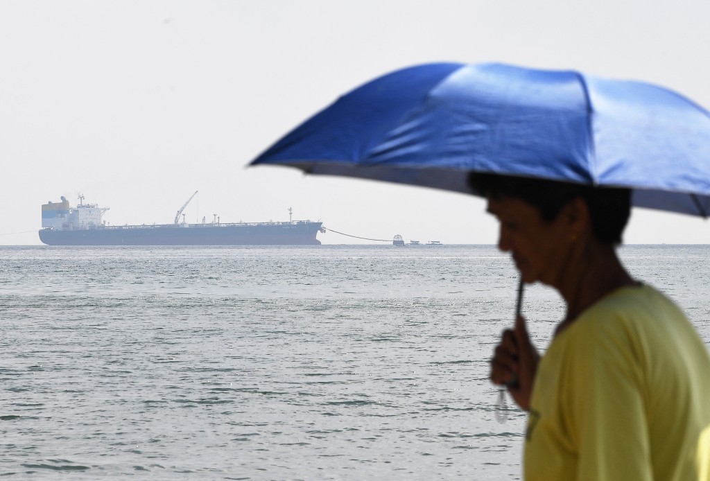 A resident stands along the seashore before the Sierra Leone-flagged Sara Sky, which is carrying crude oil from Russia, anchored at Limay port, Bataan province on March 26, 2026. (Photo by Ted ALJIBE / AFP)