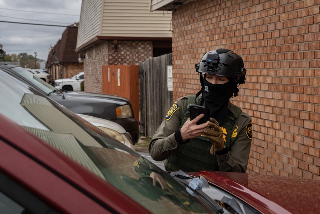Photo by ADAM GRAY / AFP A US Customs and Border Patrol agent takes a photograph of a vehicle during operations in Kenner, Louisiana, on December 8, 2025.