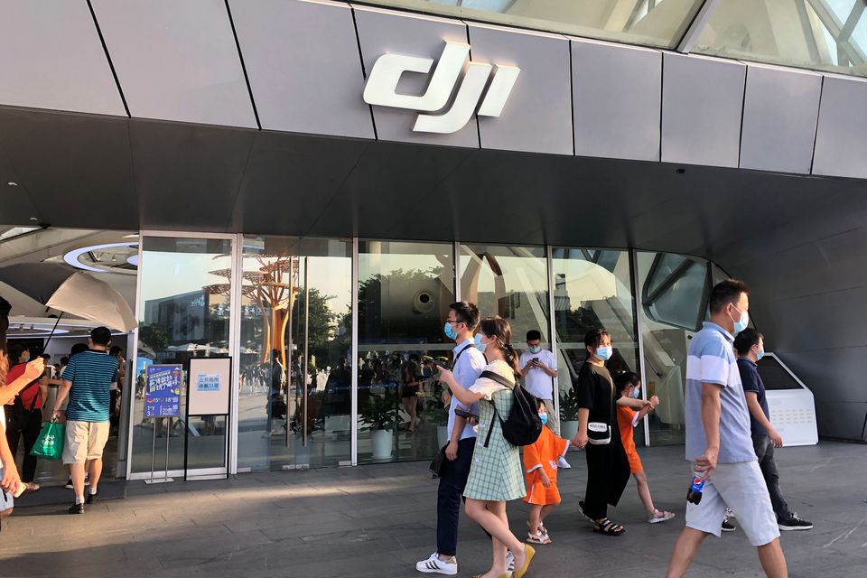 People wearing face masks following the coronavirus disease (Covid-19) outbreak walk past DJI's flagship store in Shenzhen, Guangdong province, China. (Reuters) People wearing face masks following the coronavirus disease (Covid-19) outbreak walk past DJI's flagship store in Shenzhen, Guangdong province, China. (Reuters)