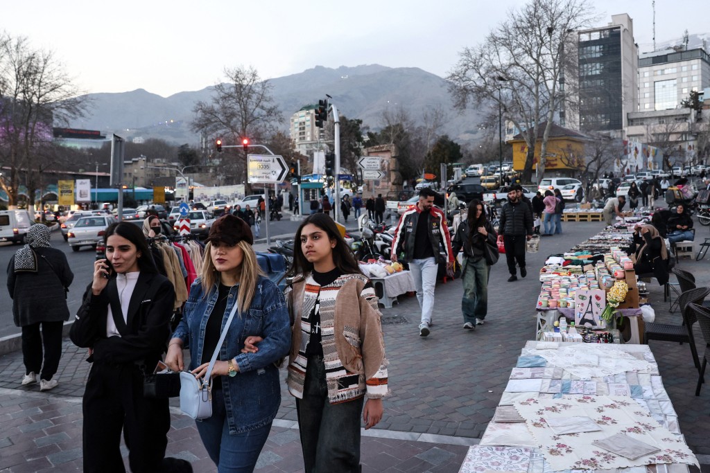 Photo by STRINGER / AFP  Iranian women walk past street vendors in northern Tehran on February 23, 2026.