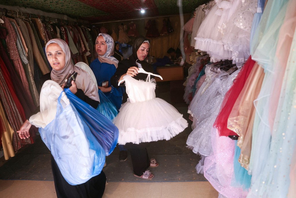Photo by BASHAR TALEB / AFP Palestinian women shop for dresses worn on special occasions at a workshop where dresses are created including evening and wedding gowns despite limited resources and old dresses are recycled, in the city of Khan Yunis in the southern Gaza Strip on June 13, 2026.