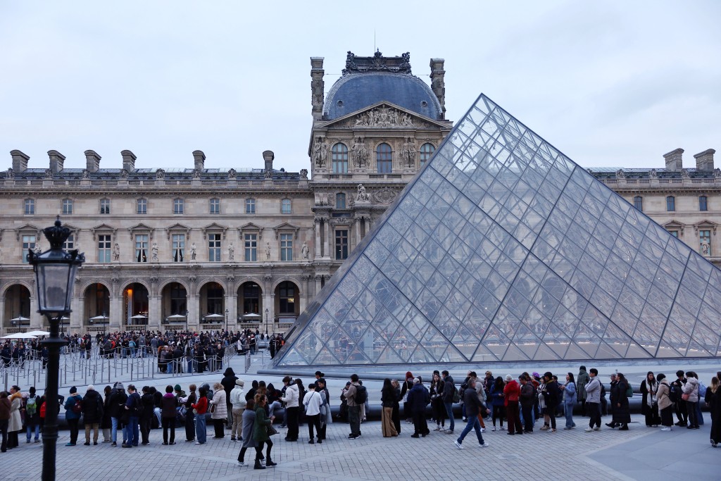 People queue near the glass Pyramid of the Louvre Museum to enter the museum which remains closed as its staff continue discussions on whether to extend a strike over pay and working conditions at the museum, the state of the museum's buildings and staffing issues, two months after a spectacular heist which saw thieves make off with jewels in broad daylight, in Paris, France, December 17, 2025. REUTERS/Abdul Saboor