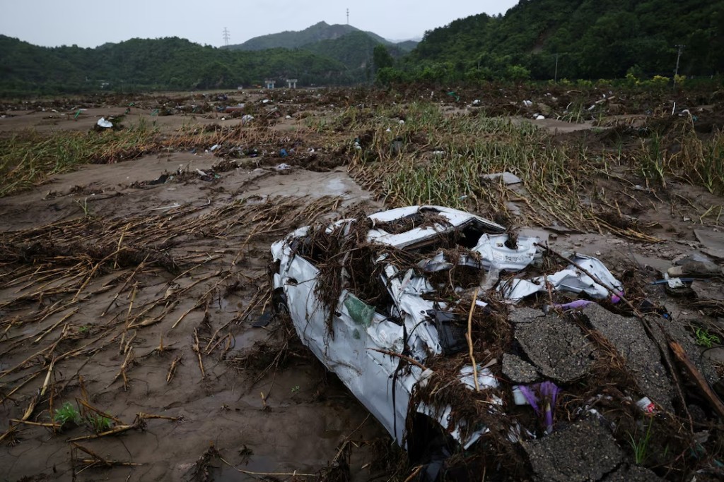  A damaged car lies at a damaged corn field along the bank of the Liuli River, after heavy rains in late July that flooded the village, in Huairou district of Beijing, China, August 13, 2025. REUTERS/Tingshu Wang/File Photo