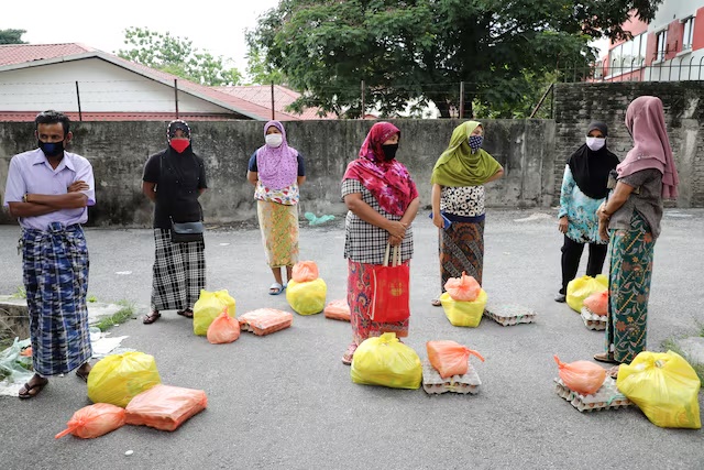 FILE PHOTO: Rohingya refugees wearing protective masks keep a social distance while waiting to receive goods from volunteers, during the movement control order due to the outbreak of the coronavirus, in Kuala Lumpur, Malaysia April 7, 2020. REUTERS/Lim Huey Teng/File Photo