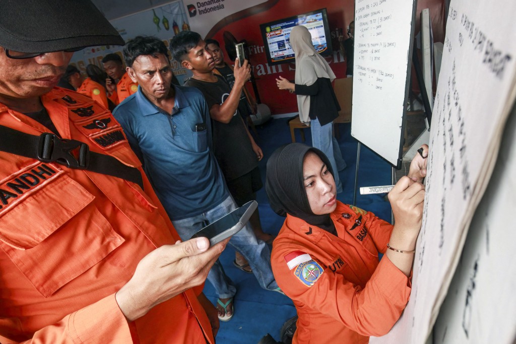 Relatives of affected passengers look on as a National Search and Rescue Agency (Basarnas) officer writes updates on a whiteboard amid ongoing rescue operations . (AFP)